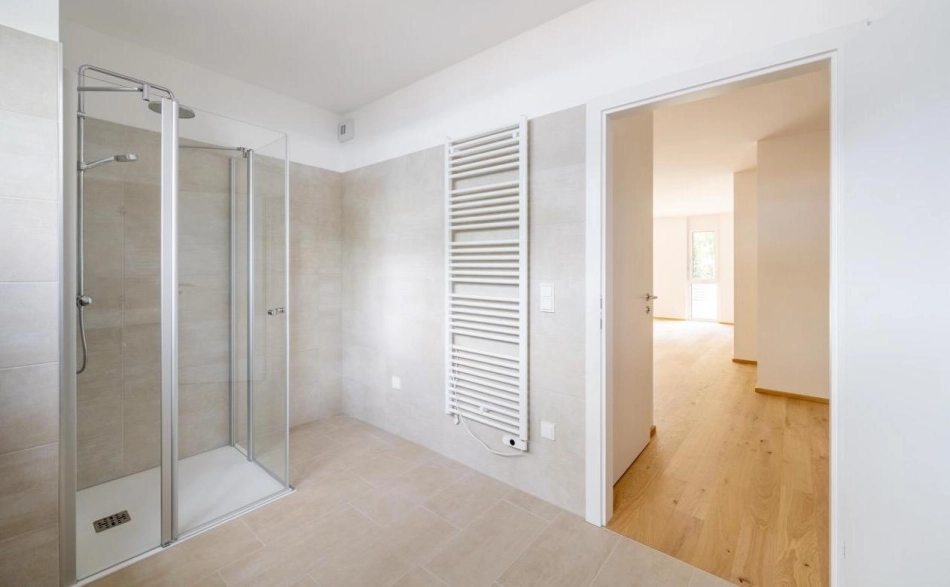 Stefan Kristoferitsch Badezimmer mit Dusche und Wandheizkörper mit Blick in einen anderen Raum, Wohnanlage Janzgasse.