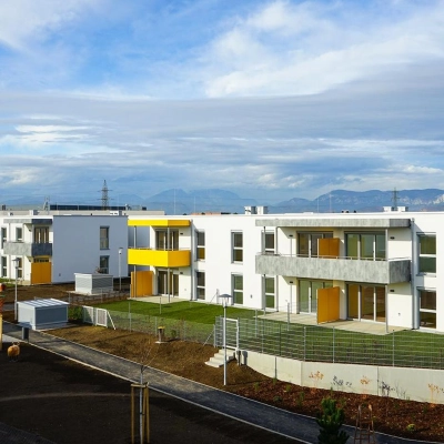 EBSG Außenansicht der Wohnanlage mit Balkonen, eingezäuntem Garten und Bepflanzung, Lachtengasse.