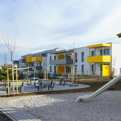 EBSG Außenansicht der Wohnanlage mit Balkonen, Spielplatz und Sitzgelegenheiten, Lachtengasse.