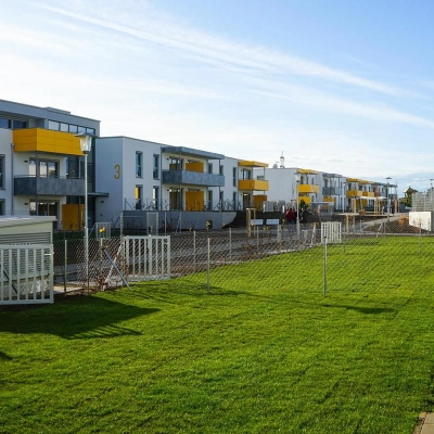 EBSG Außenansicht der Wohnanlage mit Balkonen, Zäunen und großer Grasfläche.